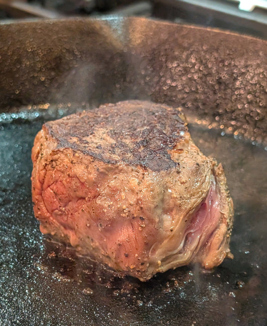 Grass-fed sirloin cooking with beef tallow in a cast iron skillet